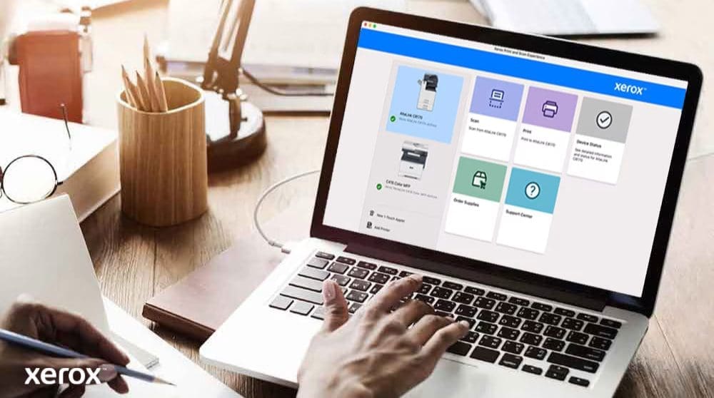 Xerox® Druck- und Scan-Erlebnis: Intuitive Steuerung Die Hände einer Person liegen auf einer Laptoptastatur und auf dem Bildschirm wird die Xerox Print and Scan Experience-Benutzeroberfläche mit Optionen wie „Scannen“, „Drucken“, „Gerätestatus“, „Verbrauchsmaterial bestellen“ und „Support Center“ angezeigt, was auf eine benutzerfreundliche Steuerung hindeutet.